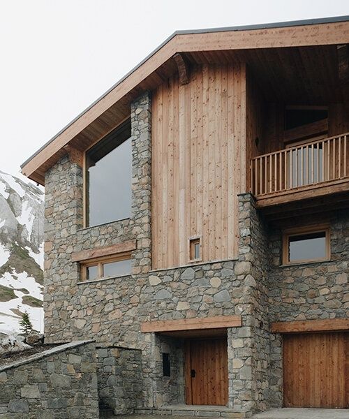 Chalet alpin en pierre et bois, avec balcon et neige en arrière-plan