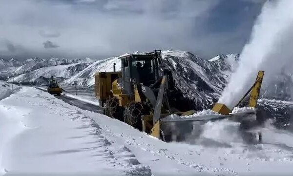 Déneigeuse ouvrant une route enneigée dans un massif montagneux