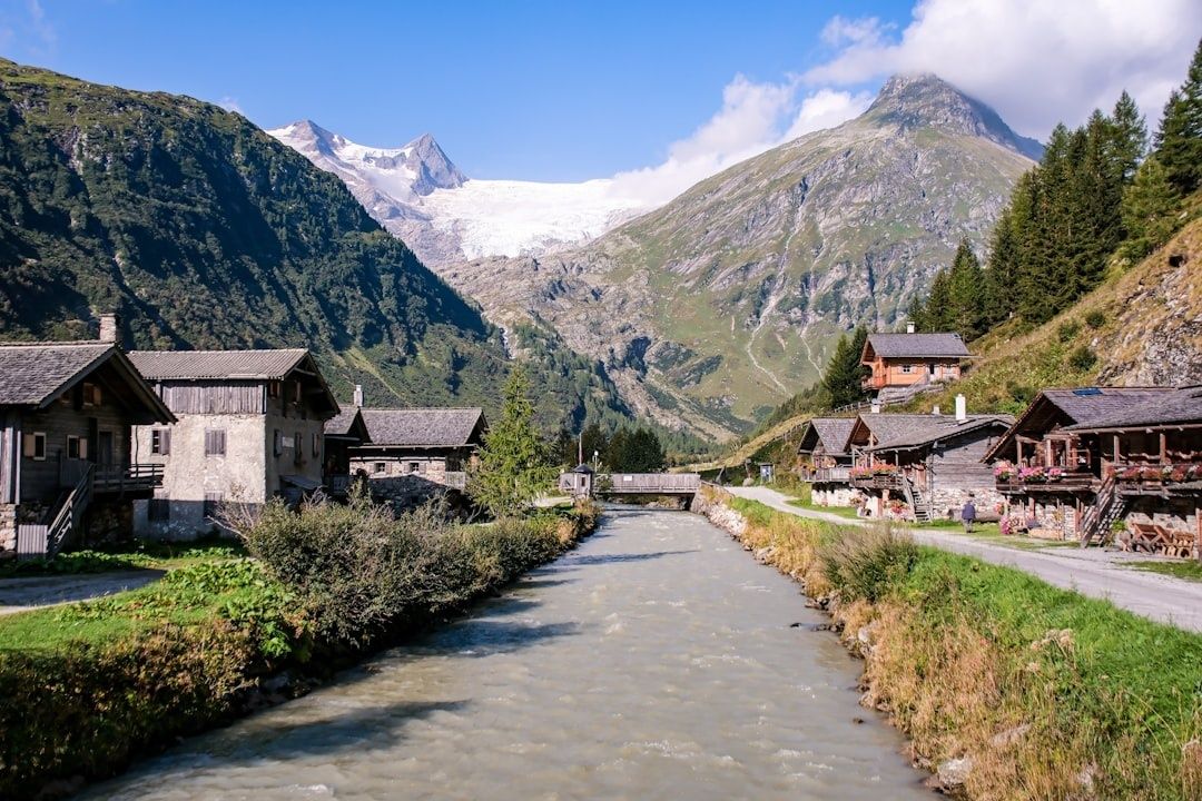 Village alpin traditionnel au bord d’un torrent, face à un glacier